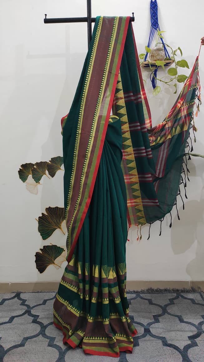 Dark green saree with thick border of geometrical pattern pleated neatly on a stand. 