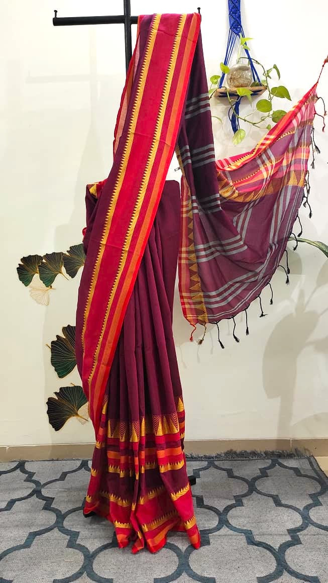 Purple saree with thick border of geometrical pattern pleated neatly on a stand. 