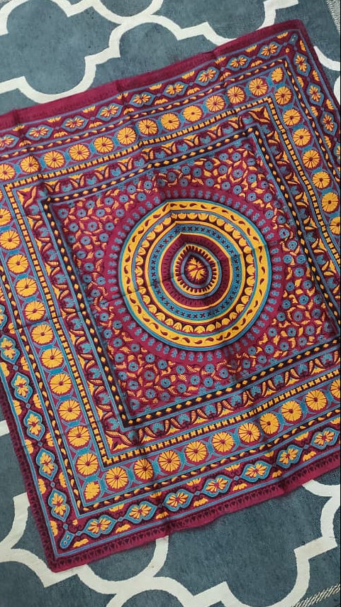 Colorful tapestry with a circular pattern on a blue and white geometric rug