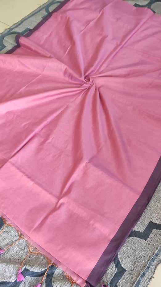 Tissue silk handloom saree draped on a saree stand which is pink in colour with copper shimmer and pink tassels