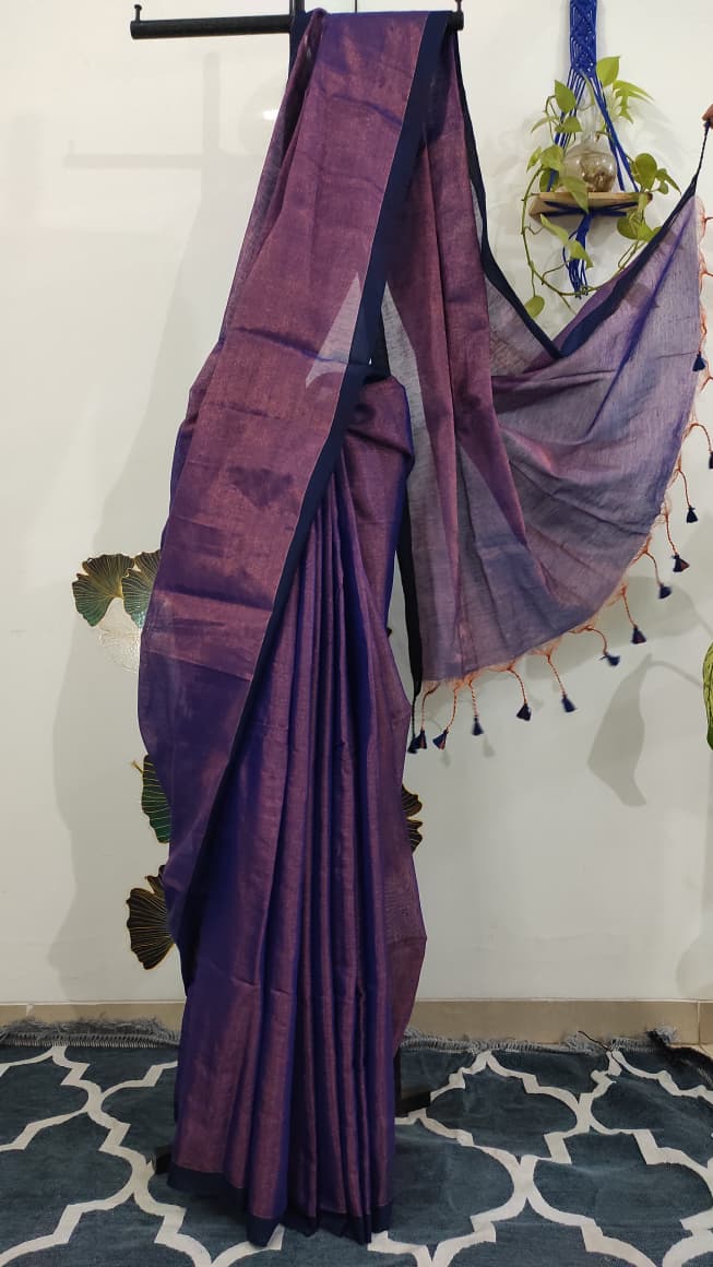 Tissue silk handloom saree draped on a saree stand which is purple in colour with copper shimmer and blue tassels
