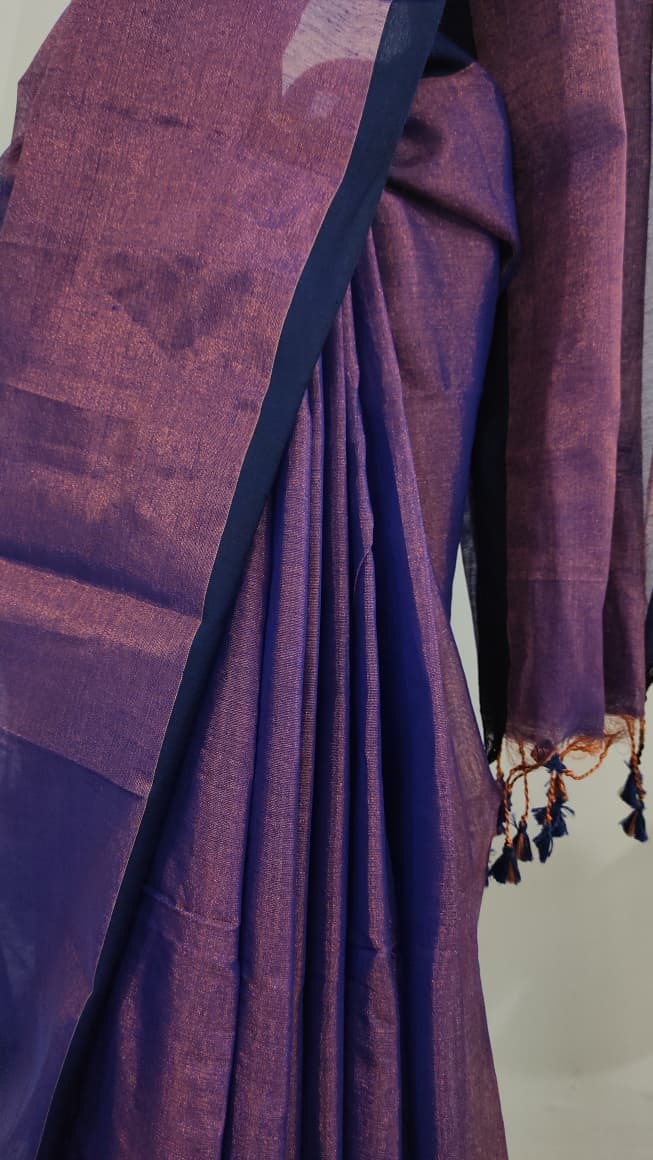 Tissue silk handloom saree draped on a saree stand which is purple in colour with copper shimmer and blue tassels.