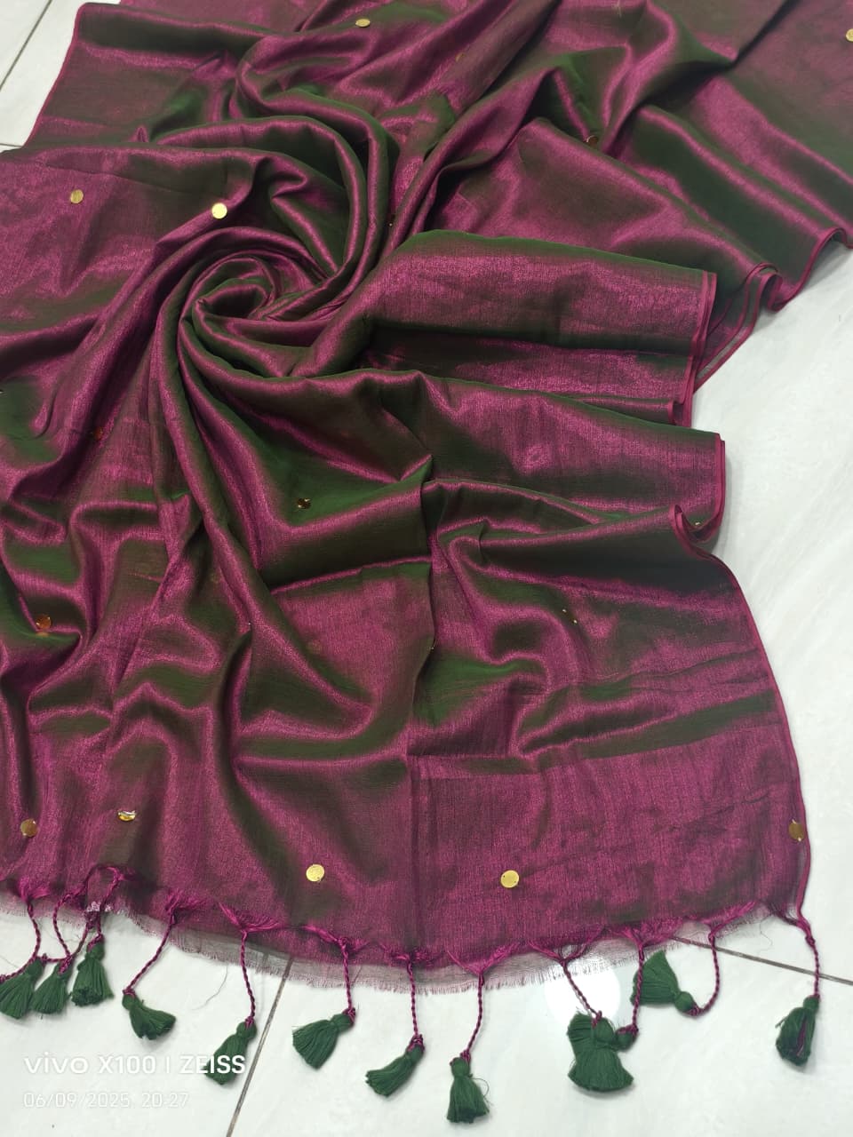 Purple handloom saree with shimmering green effect and golden  work and black tassels listed to order saree online.
